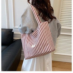 Detail of red and white striped canvas tote bag showing side label and fabric texture