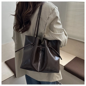 Dettaglio borsa shopper marrone scuro in pelle lucida effetto cerato con cordini