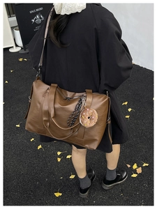 Macro view of vintage brown leather tote bag with donut pendant and canvas strap details