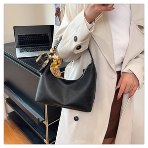 Detail of black lychee grain leather underarm bag featuring a vibrant floral silk scarf handle