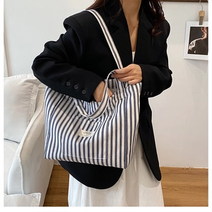 Detail of blue and white striped canvas tote bag showing the front pocket and logo label