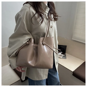 Dettaglio borsa tote in pelle verniciata beige con nodo laterale e chiusura a coulisse
