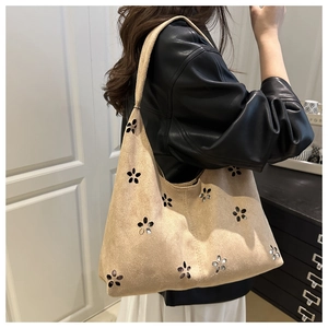 Détails des motifs floraux découpés au laser sur un sac cabas en daim beige