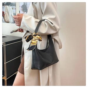 Detail of black lychee grain hobo bag with floral silk scarf on a trench coat