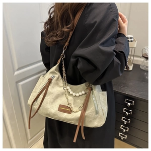 Détail du sac en toile vert sauge avec chaîne de perles et bandoulière en cuir