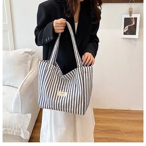 Detail of blue and white striped canvas tote bag with front pocket and logo patch