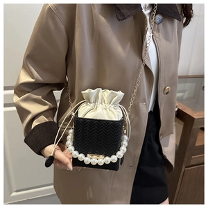 Close-up of black bucket bag featuring faux pearl accents and elegant woven texture