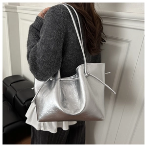 Detail of silver metallic tote bag featuring drawstring closure and textured leather