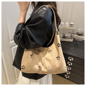 Dettaglio del motivo floreale traforato sulla borsa a spalla in pelle scamosciata beige
