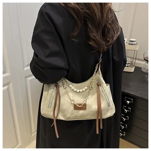Détail du sac cabas en toile vert clair avec chaînes de perles et breloques dorées