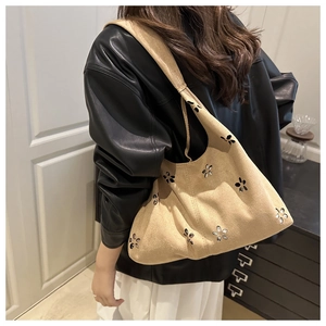 Détail des motifs floraux découpés au laser sur un sac hobo en daim beige au style rétro