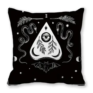 Détail de coussin noir avec imprimé blanc de serpent, chauve-souris et œil mystique