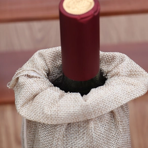Dettaglio borsa per bottiglia di vino in iuta con coulisse su tavolo di legno per Natale