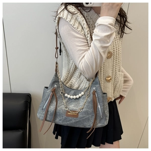 Detail of retro tote bag with pearl pendant, gold chain, and brown leather label