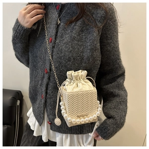 Detail view of woven leather mini bag with pearl handle and golden chain strap