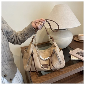 Detail of vintage hobo bag with pearl chain and crinkled leather texture in beige