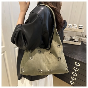 Detail of olive green tote bag with flower cutouts and metallic sequins on a model