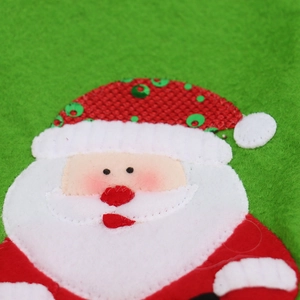 Macro detail of Santa Claus sequined embroidery on red burlap Christmas wine bag decoration
