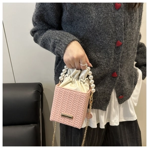 Detail of pink woven bucket bag featuring pearl handle and drawstring inner pouch