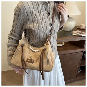 Detail of beige vintage crossbody bag featuring pearl chains and long leather tassels