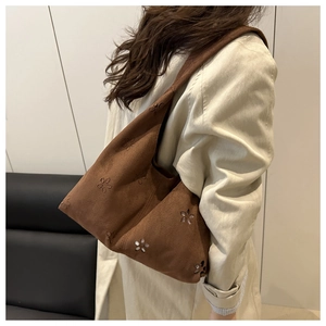 Detail einer braunen Wildledertasche mit floralem Laserschnitt-Muster auf der Schulter