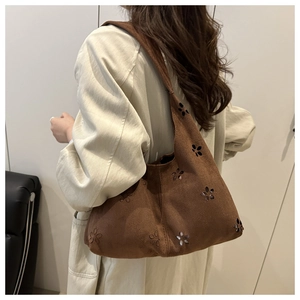 Dettaglio della borsa tote in pelle scamosciata marrone scuro con motivi floreali traforati