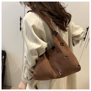 Detail of laser-cut floral patterns on brown suede hobo shoulder bag for women