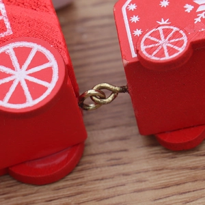 Detailed view of red wooden Christmas train carriages connected by golden metal hooks