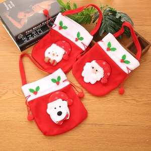 Détail de trois sacs cadeaux de Noël avec cordons et pompons sur une table en bois