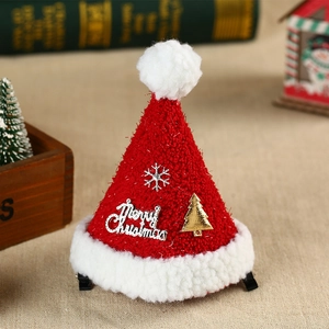 Détail d'une pince à cheveux bonnet de Noël tricoté rouge avec lettrage argenté