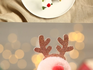 Detail of Christmas reindeer antler hair clips with gold glitter and pink plush pom-poms
