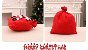 Détail du sac cadeau de Noël rouge avec cordon de serrage et application de Père Noël brodé