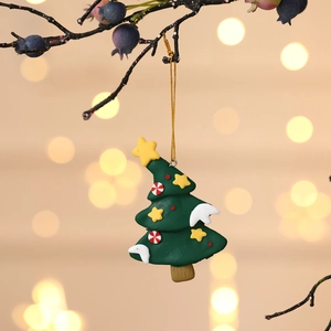 Detailed view of a green Christmas tree ornament hanging on a winter berry branch with bokeh