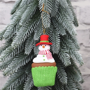 Detailed view of snowman cupcake Christmas ornament hanging on a snowy festive tree branch