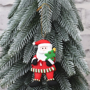 Close-up of a Santa Claus ornament holding a Christmas tree hanging on a pine branch