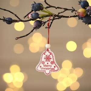 Detail of wooden Christmas bell ornament with Merry Christmas text on a festive branch