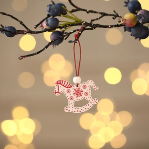 Close-up of a Nordic-style wooden rocking horse ornament hanging on a festive branch