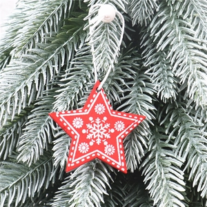 Close-up of red wooden star ornament with white snowflake on frosted pine branches
