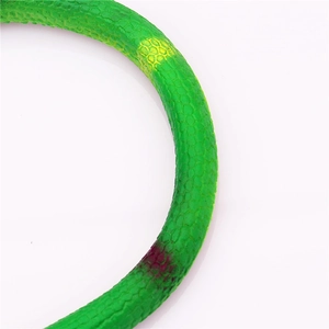 Macro detail of realistic green rubber snake toy featuring textured scales and yellow spots