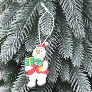 Détail d'un bonhomme de neige en bois avec bonnet rouge et cadeau sur branche de sapin