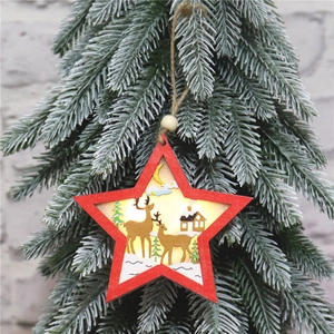 Close-up of a red wooden star ornament with glowing reindeer scene on pine tree branches