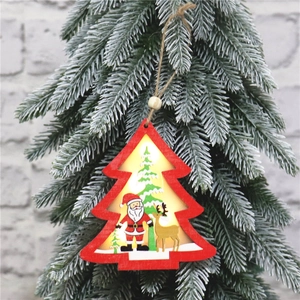 Close-up of a lit wooden Christmas tree pendant with Santa Claus hanging on fir branches