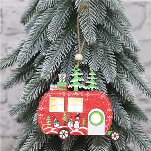 Close-up of red wooden RV Christmas ornament with LED lights hanging on a tree branch