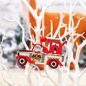 Détail d'un camion de Noël rouge en bois avec texte Joy suspendu à une branche enneigée