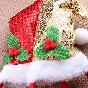 Detail der roten und goldenen Pailletten-Weihnachtsmützen mit weißem Plüsch und Stechpalmen