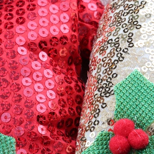 Detail von roten Pailletten und Stechpalmenblatt an einem festlichen Weihnachtsstirnband