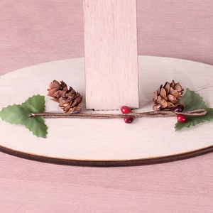 Detail of wooden Christmas base with natural pine cones, red berries and green leaves