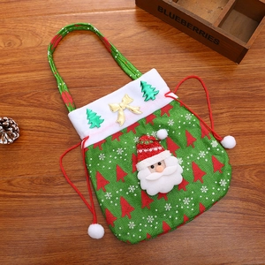 Detail of green burlap Christmas gift bag with plush Santa Claus and festive patterns
