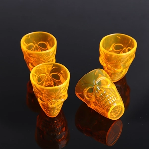 Set of four orange skull shot glasses with 3D bone details for Halloween party decor