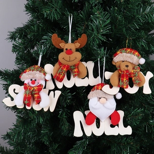Dettaglio ornamenti natalizi in peluche con scritte in legno SNOW, NOEL, JOY su albero